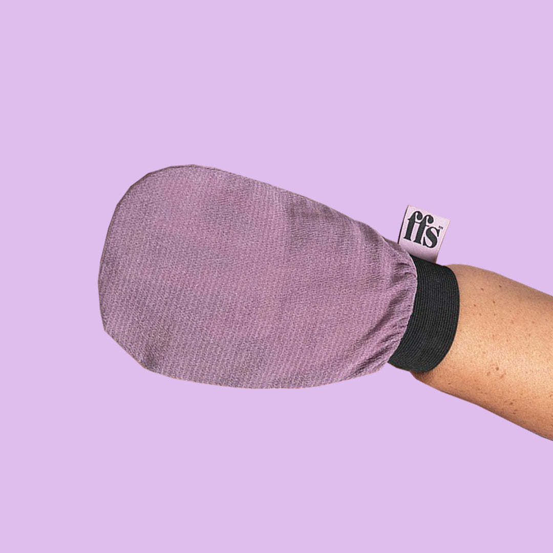 Woman wearing an ffs exfoliating mitt on her hand